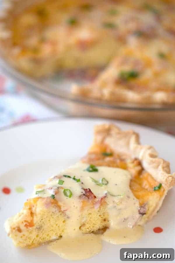 Ham quiche on a white plate with hollandaise sauce drizzled over the top.