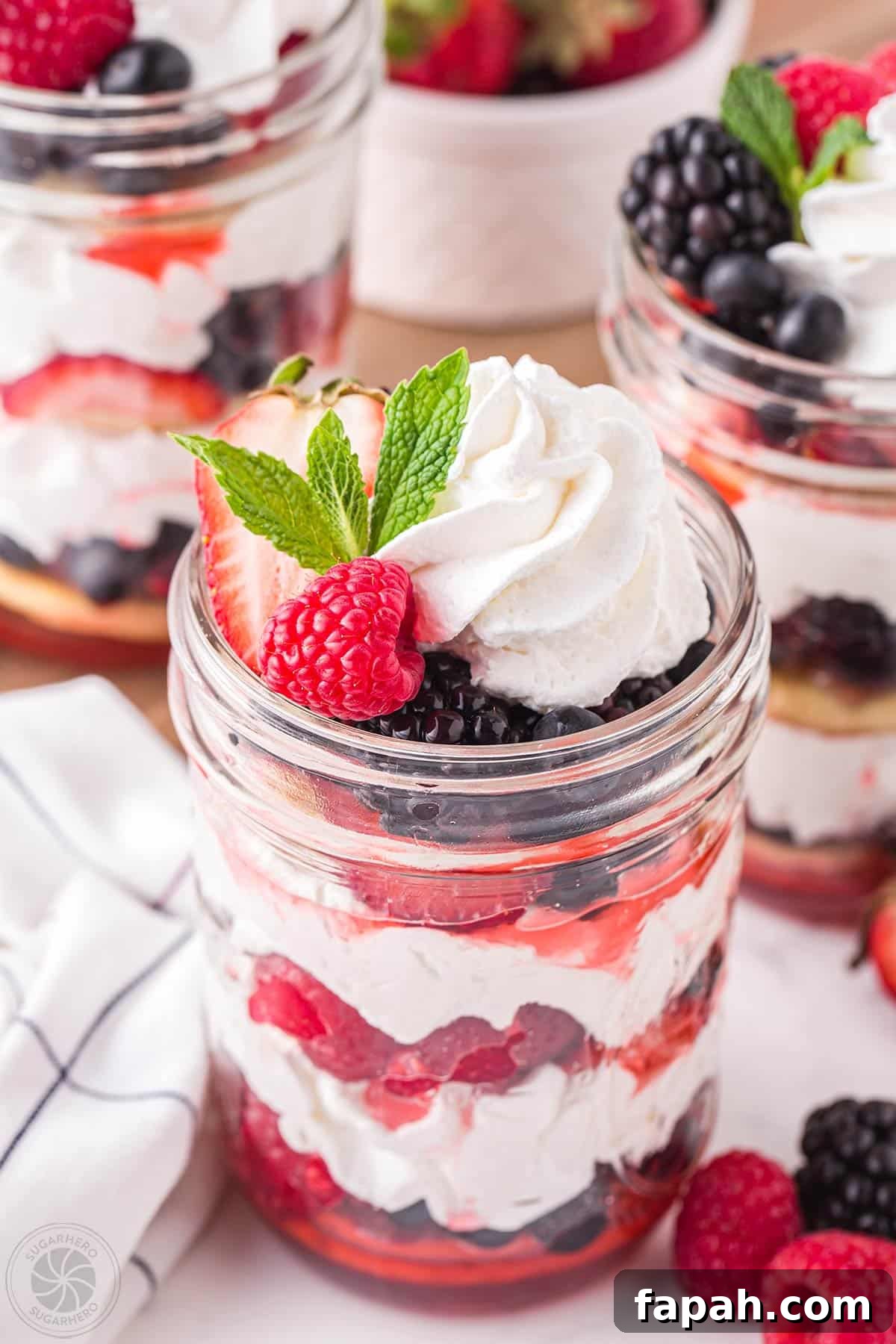 Mixed berry shortcake in a jar with berries, whipped cream, and shortcakes