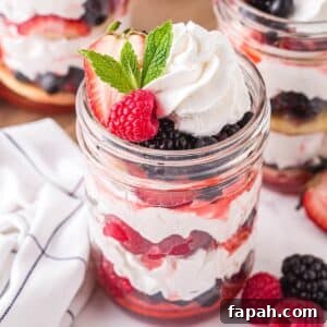 Three jars of mixed berry shortcake with berries, whipped cream, and shortcakes.