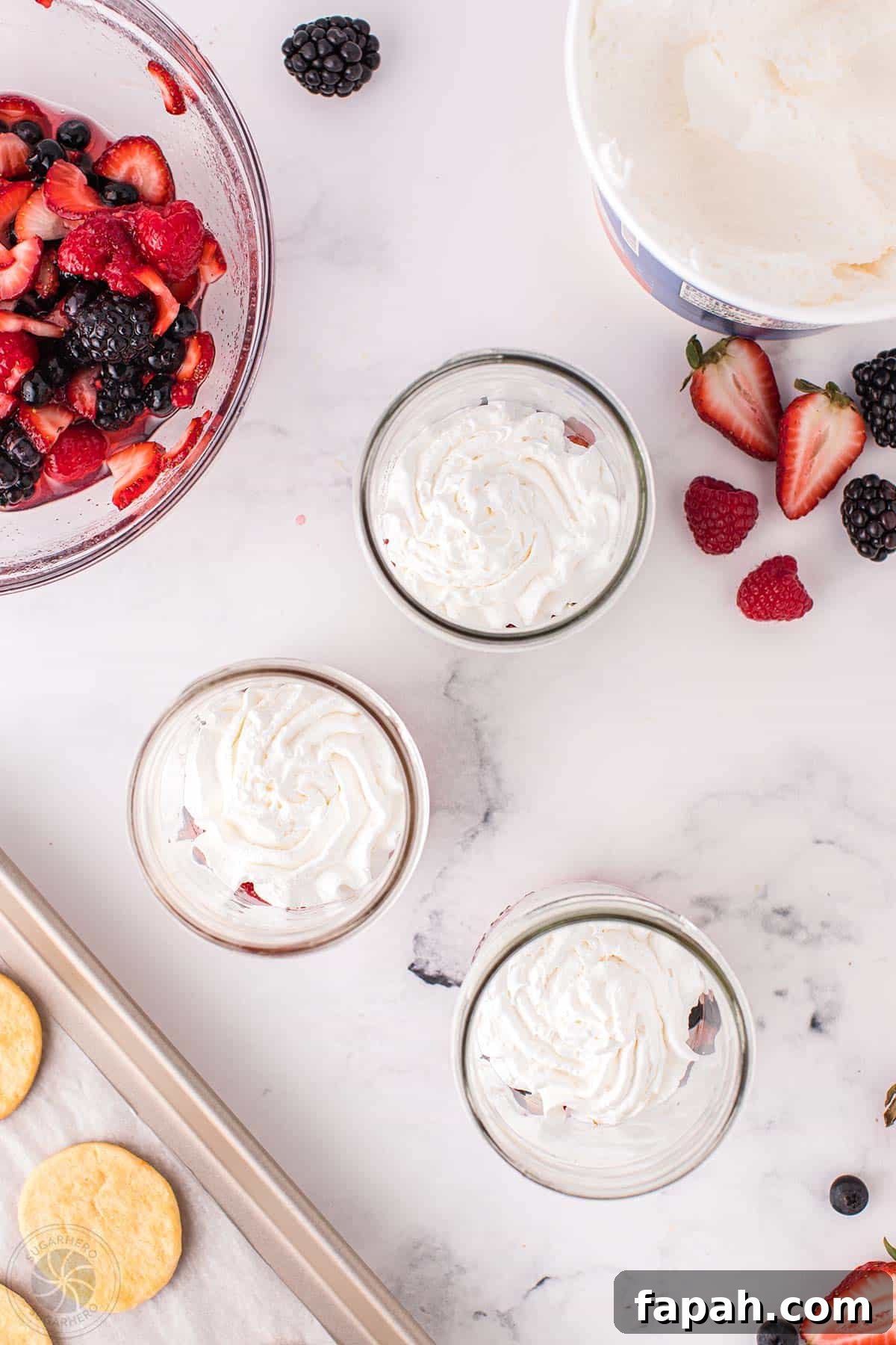 Swirls of whipped cream on top of mixed berries in mason jars.