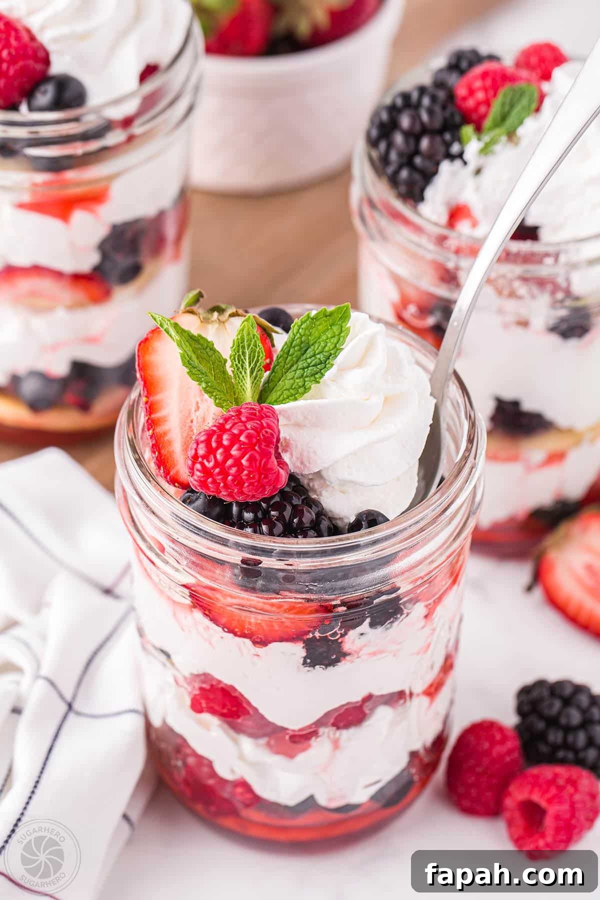 Mixed Berry Shortcakes in mason jars with a spoon sticking out of one