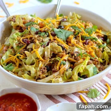 Taco salad in a white bowl with fresh cilantro and salsa.