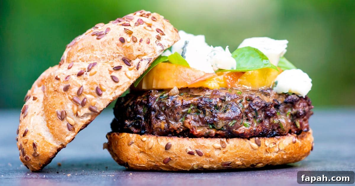 a delicious hamburger made from venison meat with peaches on top with a seeded bun