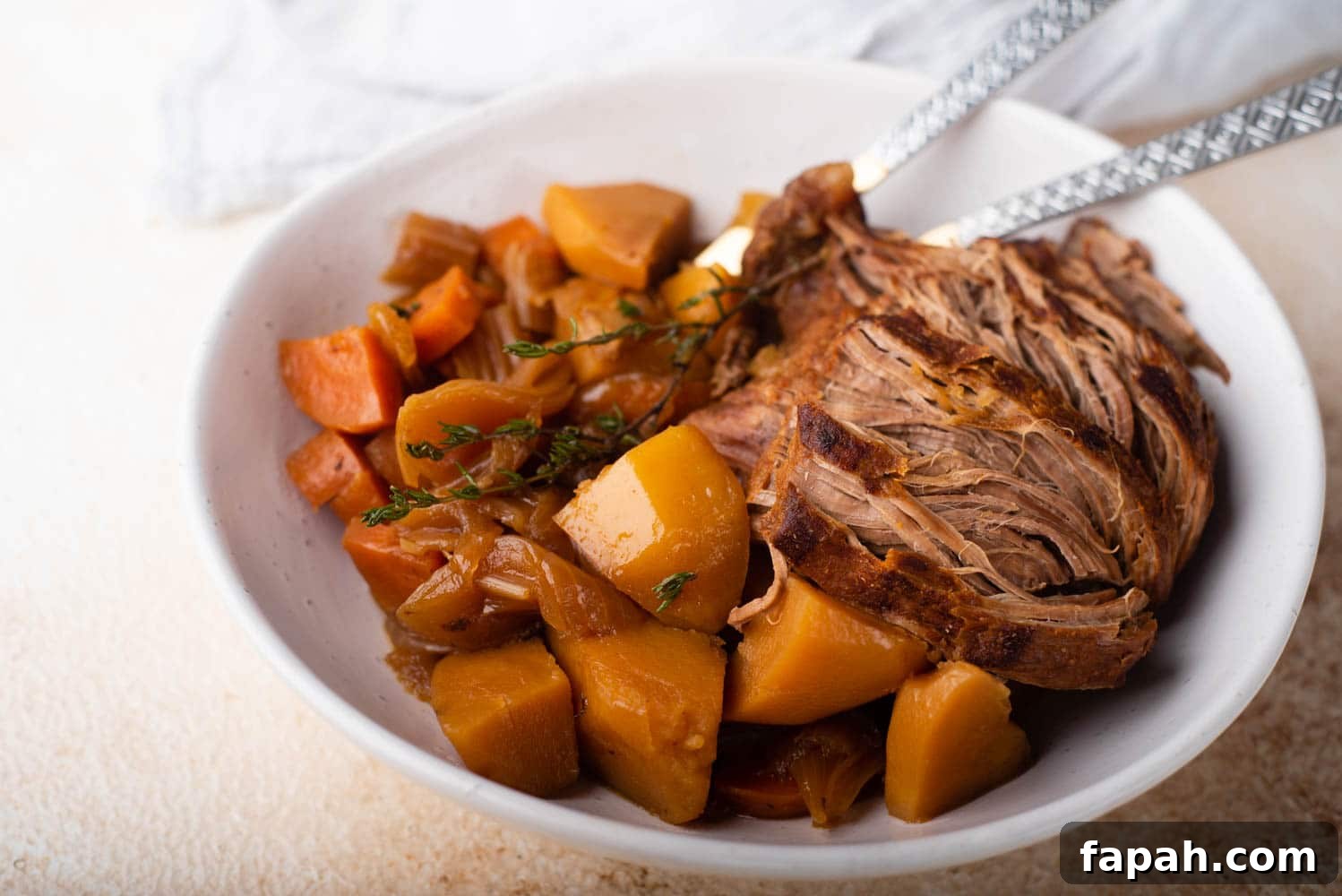 bowl of venison roast with potatoes and carrots. Serving spoons sitting in the bowl.