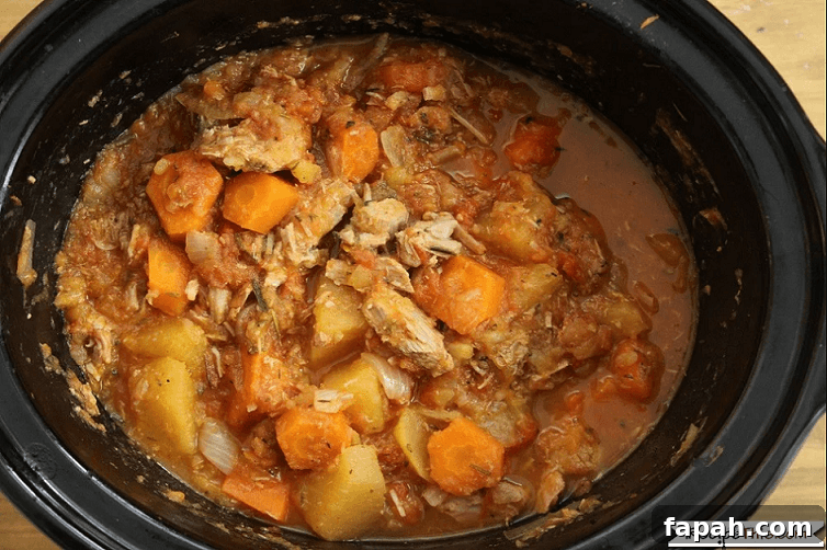 a slow cooker filled with venison stew with carrots and potatoes
