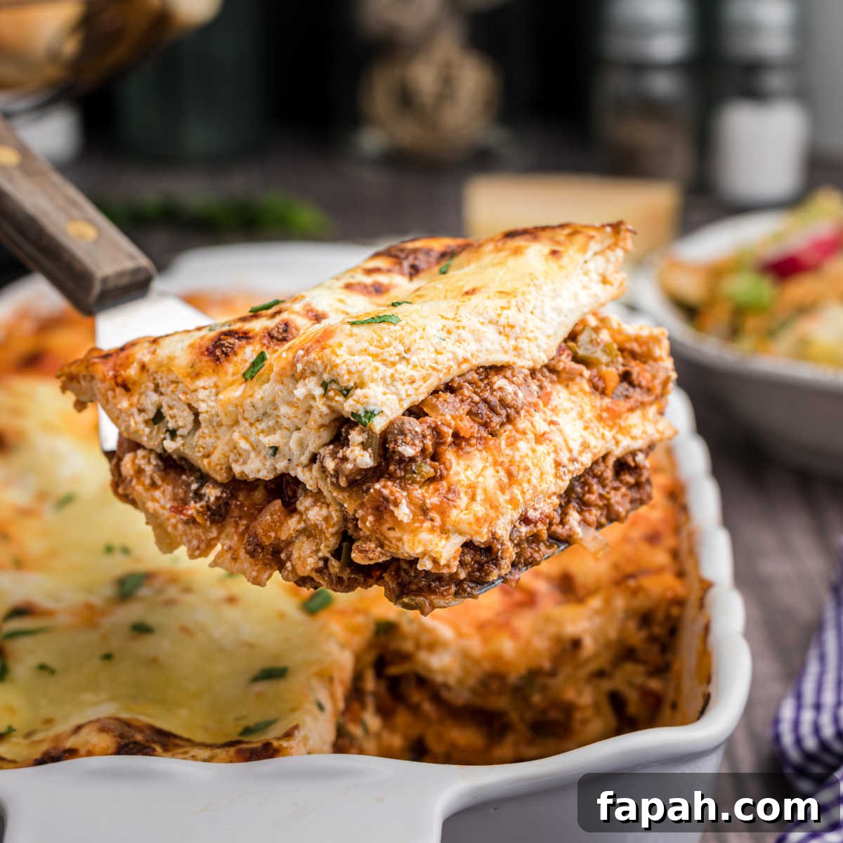 A scoop of venison lasagna being lifted out of the dish.