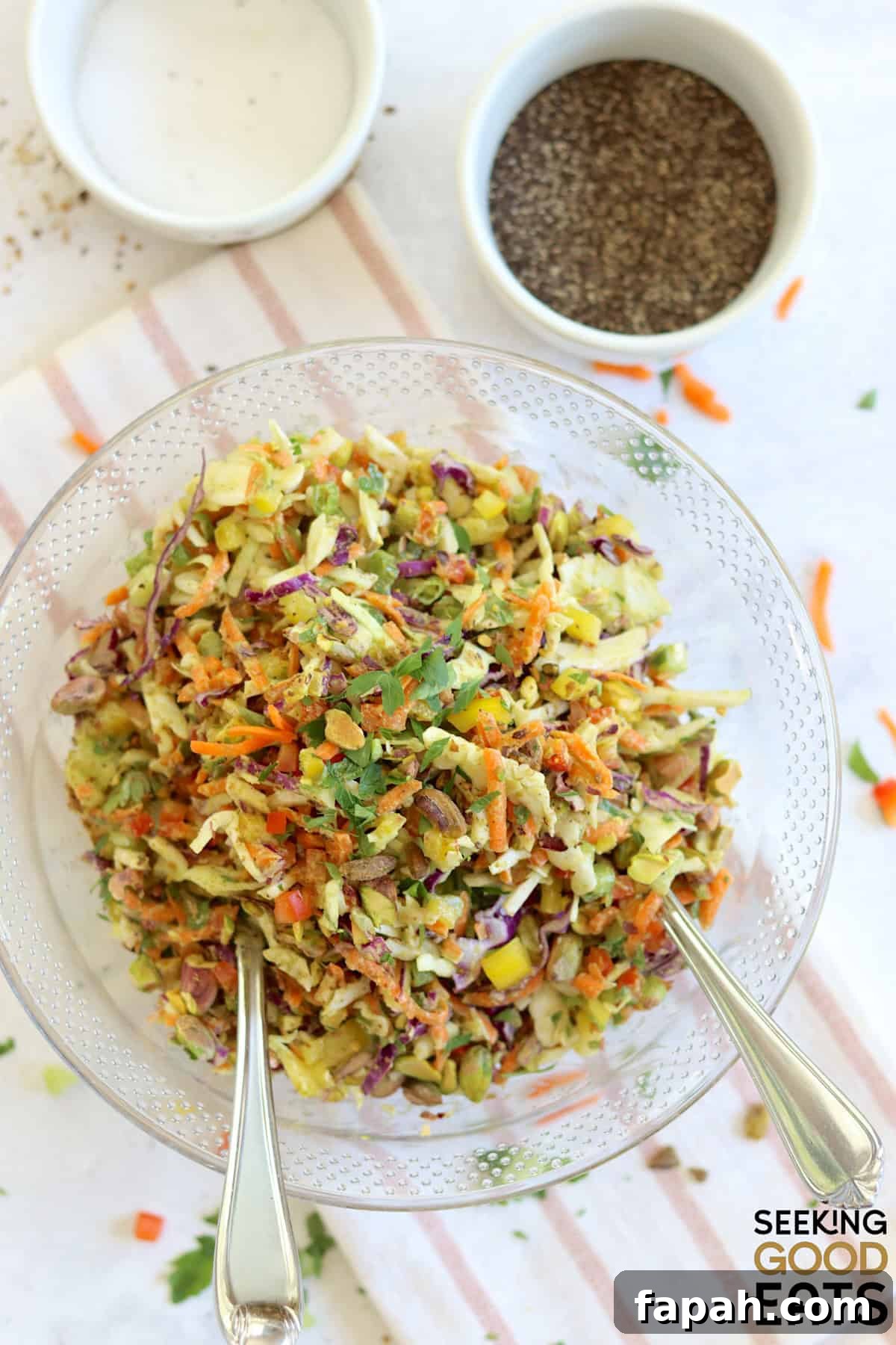 Green goddess cabbage salad served in a large clear bowl and two silver serving spoons.