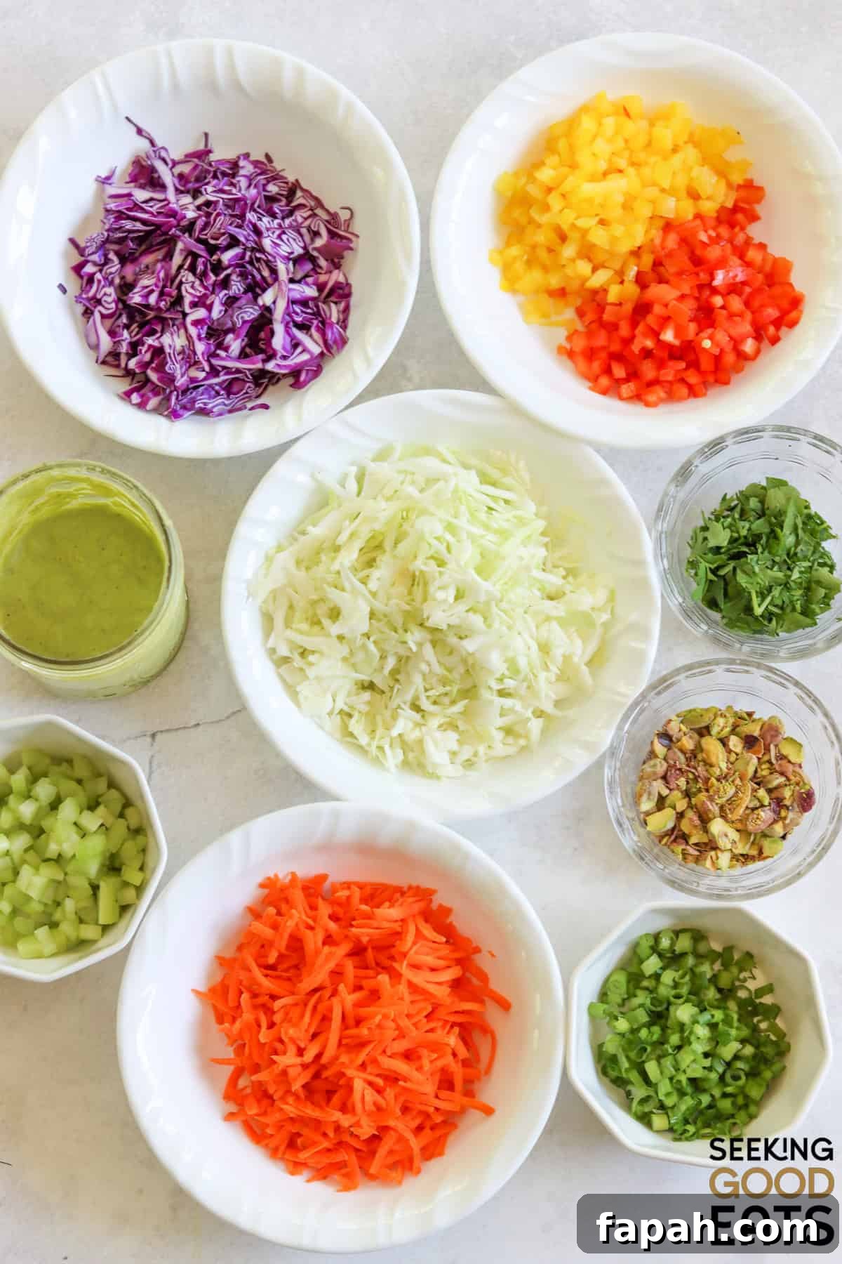 Ingredients needed to make green goddess cabbage salad arranged on a white marble countertop.