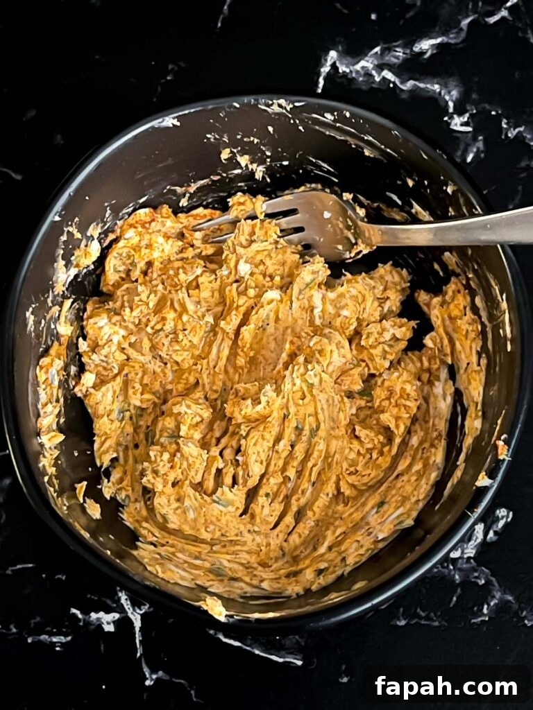 Lemon herb compound butter combined in a dark bowl on a dark surface.