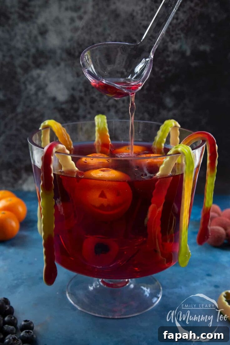 Clear glass punch bowl with ladle and floating spooky fruit jack-o'-lanterns and eyeballs