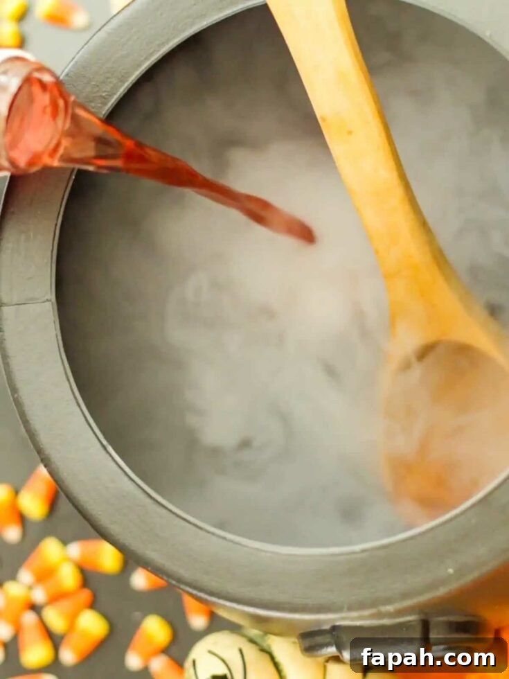 Wooden spoon stirring red liquid in a smoky cauldron-shaped punch bowl