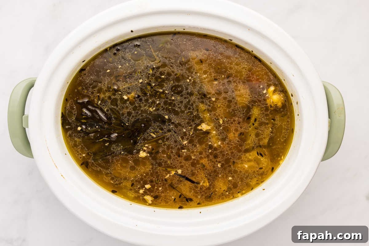 dark bone broth cooking in slow cooker.