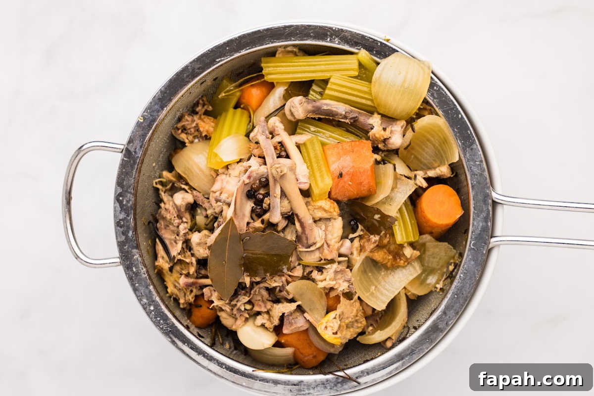 bones and veggie scraps in strainer over bowl.