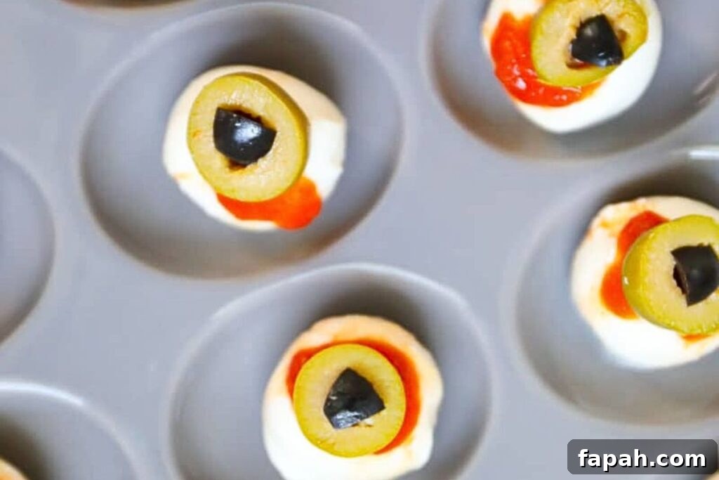 A tray of mozzarella balls with sauce and olives.